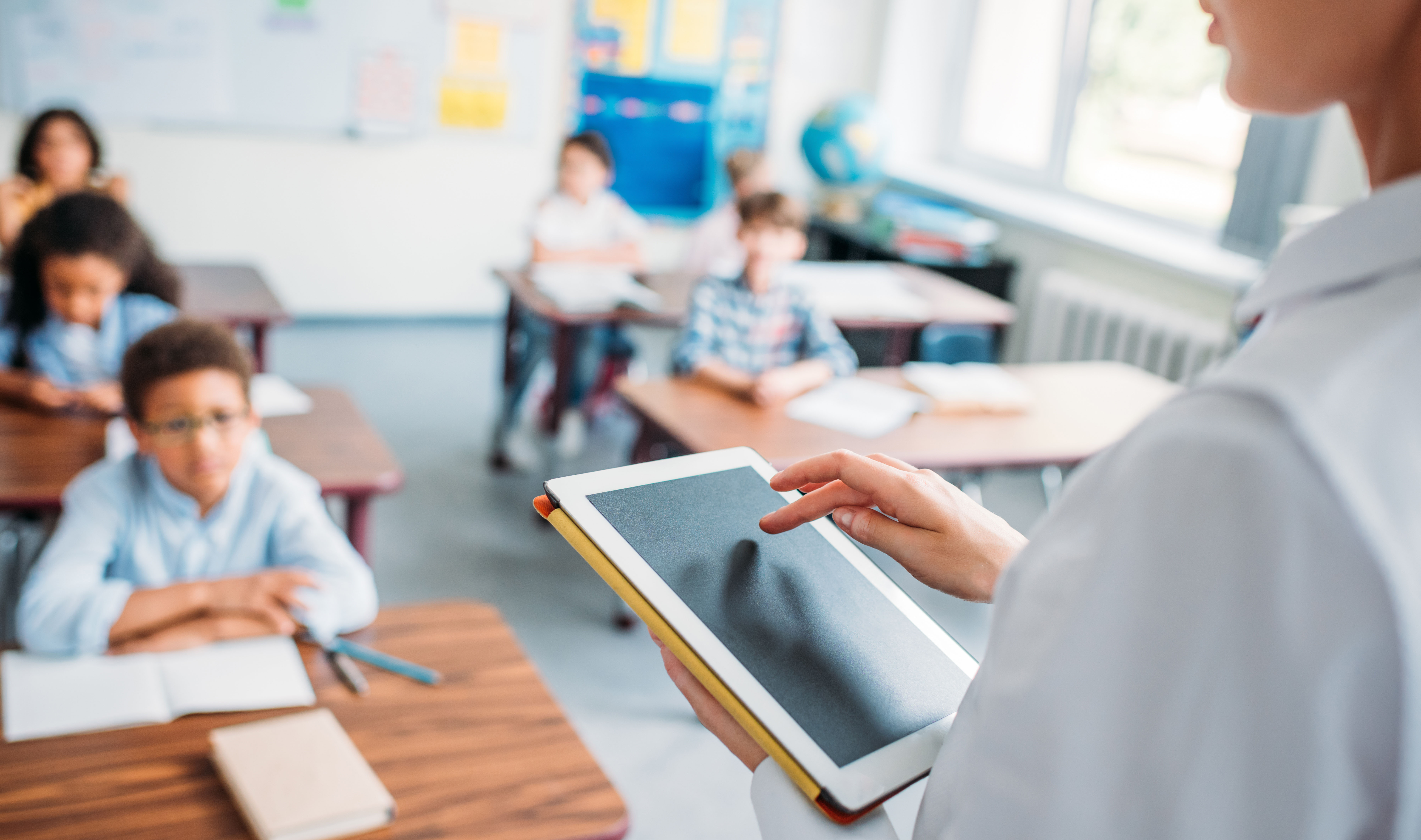 A teacher stands in front of a classroom